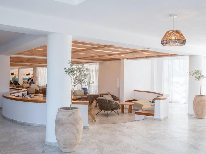 Bright hotel lobby area with white walls, seating, and large ceramic vases.