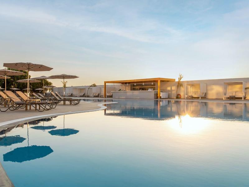 Modern pool area with lounge chairs and umbrellas at sunset.