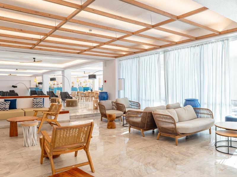 Bright hotel lounge area with comfortable chairs, sofas, and large windows.