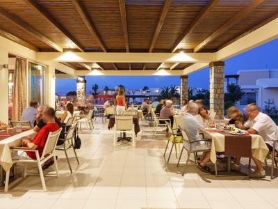 Restaurante abierto con comensales cenando bajo un techo de madera al anochecer, disfrutando la vista.