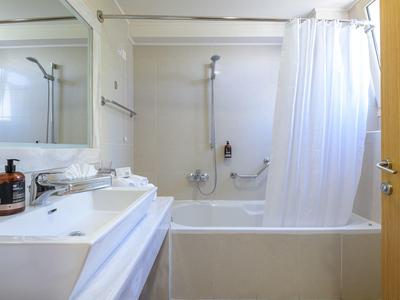 Baño luminoso con bañera blanca, cortina, lavabo y espejo grande.