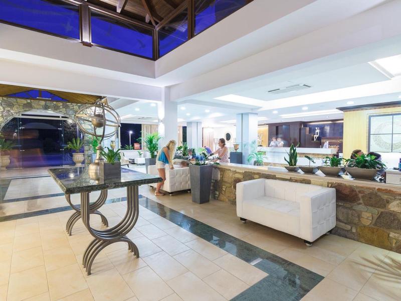 Recepción moderna de hotel con muebles elegantes, planta decorativa y luz natural abundante