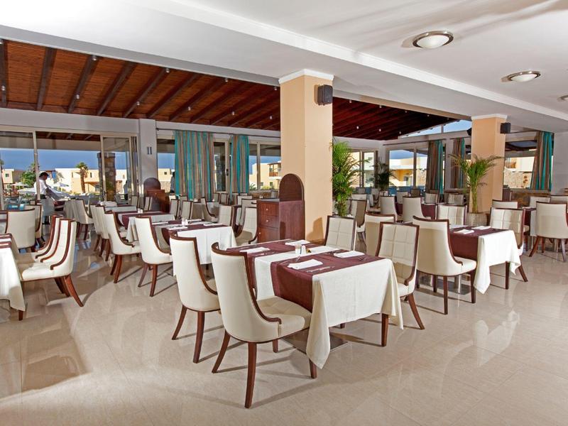 Un restaurante amplio con sillas blancas y mesas con manteles blancos y marrones.