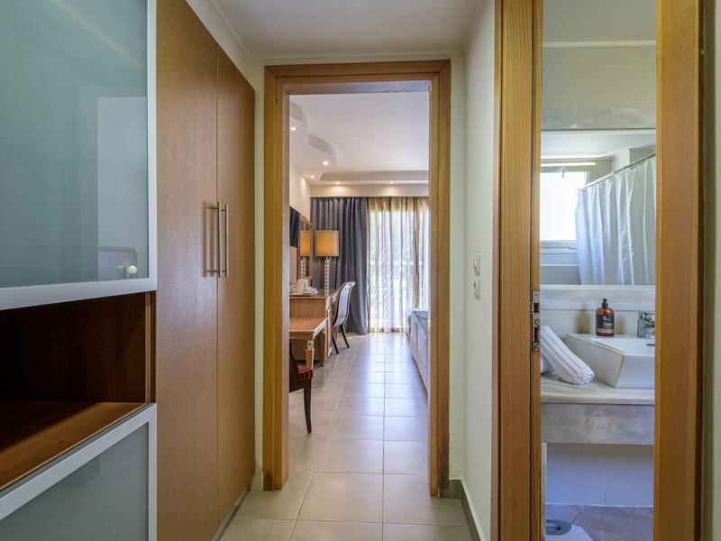 Pasillo con vista a una sala luminosa y un baño en una habitación de hotel.