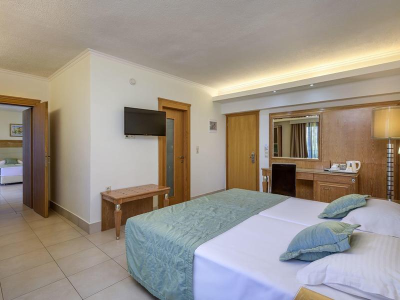 Habitación de hotel luminosa con cama doble, televisor plano y escritorio con iluminación.