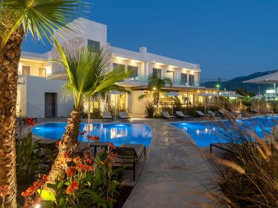 Hotel illuminato con piscina invitante e palme al crepuscolo.