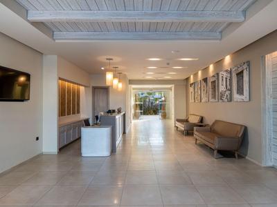 Jasne lobby hotelowe z miejscami do siedzenia, recepcją i nowoczesnym oświetleniem.