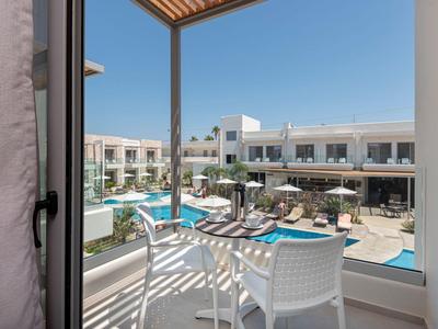 Widok z balkonu na basen z leżakami i nowoczesnym budynkiem hotelu w słoneczną pogodę.