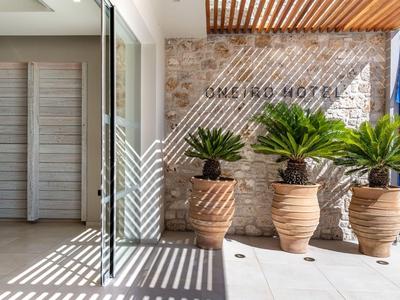 Tre grandi vasi con piante davanti a una parete di pietra con la scritta 'Bali Sky Hotel' e una parete di vetro.