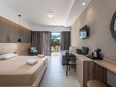 Nowoczesny pokój hotelowy z dwoma łóżkami, biurkiem, telewizorem i balkonem z widokiem.