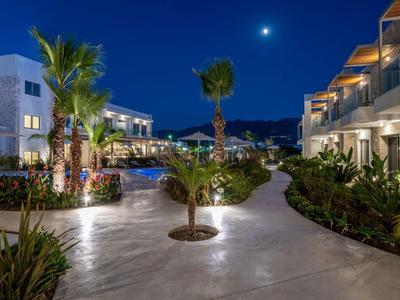 Complesso alberghiero moderno con sentieri illuminati, palme e cielo notturno limpido con luna.