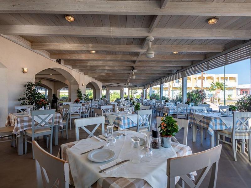 Przestronna, jasna sala restauracyjna z nakrytymi stołami i widokiem na otwarty taras.