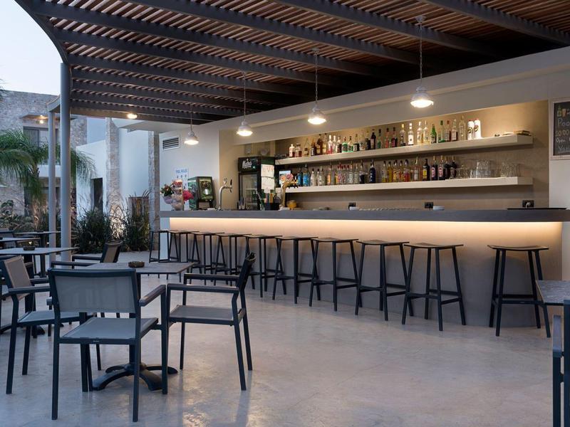 Nowoczesny bar hotelowy z miejscami do siedzenia i podświetlanym barem pod drewnianym sufitem.