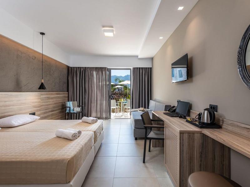 Nowoczesny pokój hotelowy z dwoma łóżkami, biurkiem, telewizorem i balkonem z widokiem.