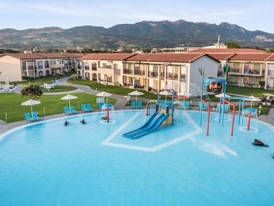 Piscina dell'hotel con scivoli e lettini davanti a uno sfondo montano.
