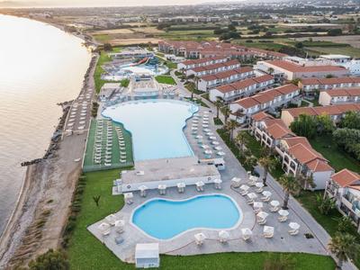 Vista aerea di un resort costiero con grandi piscine e file di edifici vicino alla spiaggia.