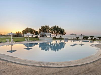 Piscina rotonda con lettini e ombrelloni al tramonto in un luogo tranquillo.