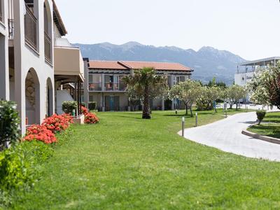 Giardino verde con fiori colorati accanto a un edificio dell'hotel e montagne sullo sfondo.