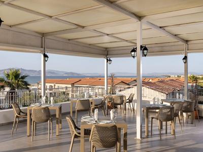 Terrazza esterna coperta con tavoli e sedie con vista sul mare e sui tetti.