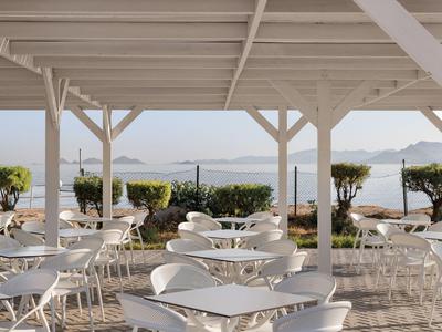 Terrazza all'aperto con sedie e tavoli bianchi con vista sul mare e sulle isole.