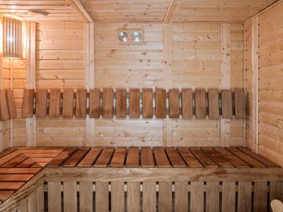 Interno sauna in legno con panche e illuminazione calda.