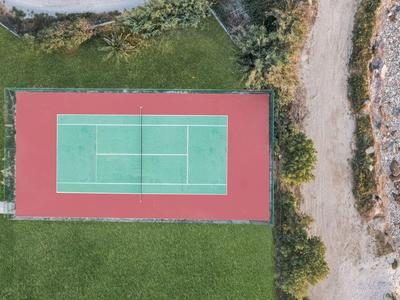 Veduta aerea di un campo da tennis accanto a un sentiero e aree erbose.