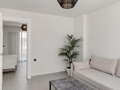 Camera d'hotel minimalista con divano grigio, tavolino nero e pianta in vaso.