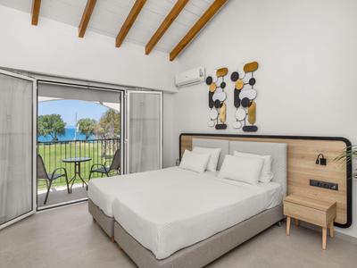 Camera moderna con letto grande e porte scorrevoli che si aprono su un giardino con vista piscina.