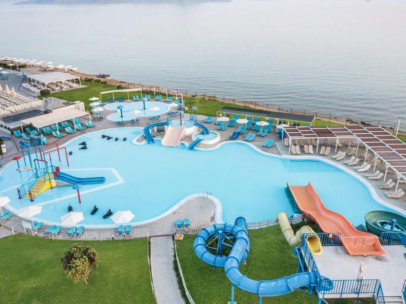 Parco acquatico all'aperto con piscine, scivoli e sedili vicino all'acqua.