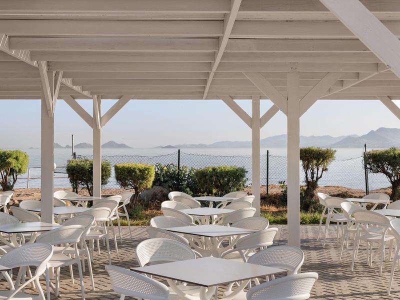 Terrazza all'aperto con sedie e tavoli bianchi con vista sul mare e sulle isole.