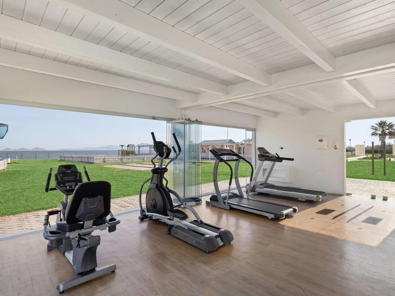 Palestra moderna con macchine cardio e vista aperta su spazio verde esterno.