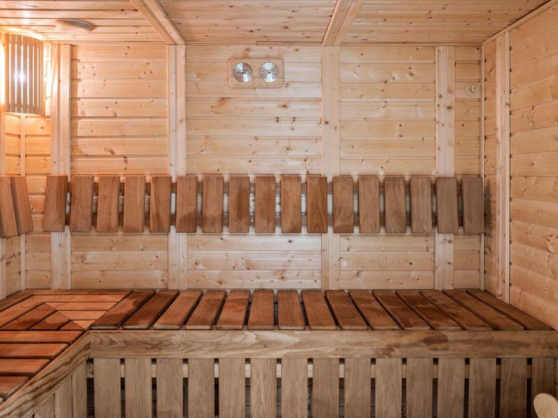 Interno sauna in legno con panche e illuminazione calda.