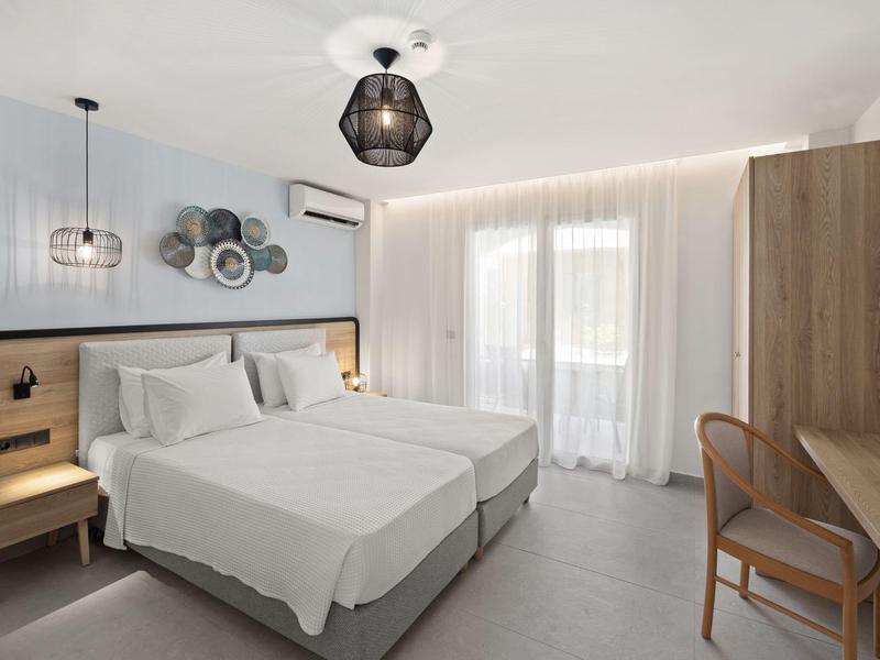 Camera d'hotel moderna con due letti singoli, toni neutri, mobili in legno e illuminazione soffusa.