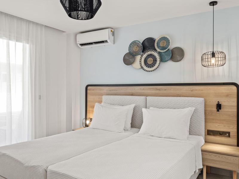 Camera d'hotel moderna con due letti, lenzuola bianche, testiera in legno e decorazione murale.