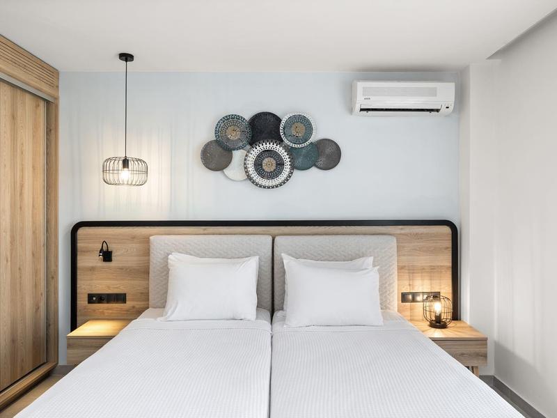 Camera d'hotel minimalista con due letti singoli, testiera in legno e decorazioni murali.