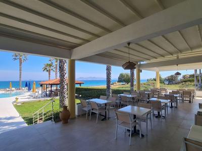 Terrazza coperta con tavoli e sedie con vista sulla piscina e sul mare.