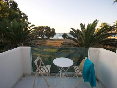 Malý balkón se stolem, dvěma židlemi a výhledem na moře při západu slunce.