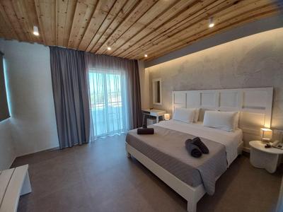 Camera d'hotel moderna con soffitto in legno, grande finestra, letto matrimoniale e arredi eleganti.