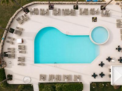 Moderner Hotelpool mit Liegestühlen und klarem, blauem Wasser in sonniger Umgebung.