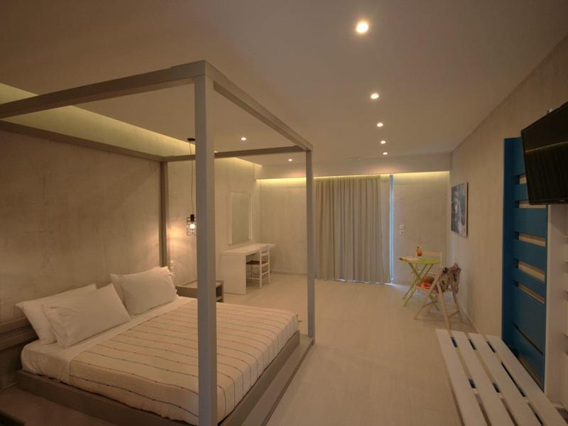 Moderní hotelový pokoj s postelí s nebesy, psacím stolem a televizí v teplých tónech.