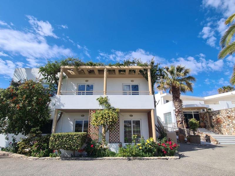 Dvoupodlažní bílý dům s balkonem a palmami pod modrou oblohou