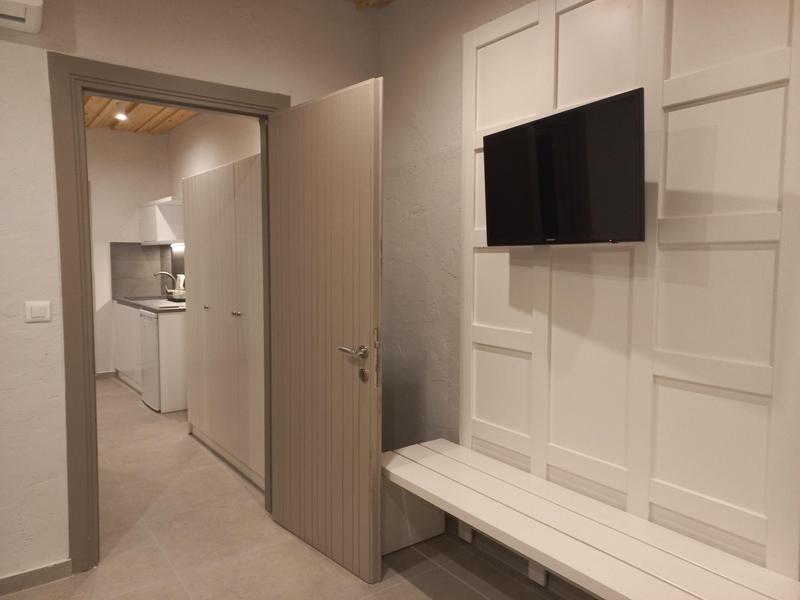 Moderní hotelová chodba se světlými stěnami, dveřmi do chodby a televizí na zdi.