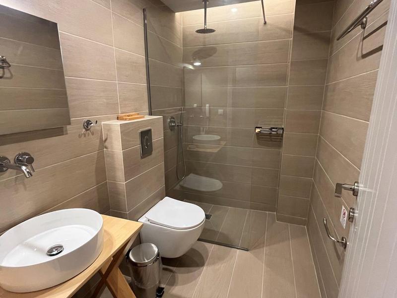 Moderní koupelna s bezbariérovým sprchovým koutem, umyvadlem na dřevěné desce a závěsným WC.