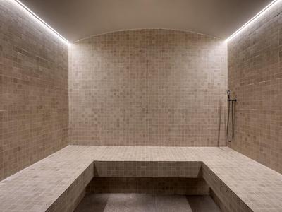 Modern steam room with illuminated ceiling edges and mosaic wall tiles.