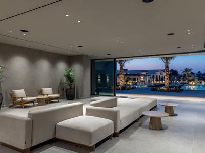 Modern hotel lounge area with white sofa and view of pool and evening sky.