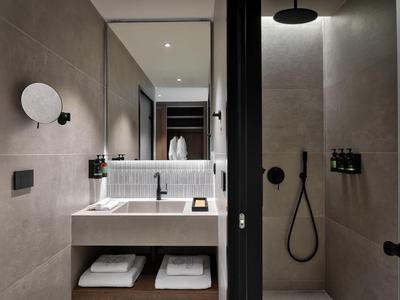 Modern bathroom mirror with sink and walk-in shower in muted tones