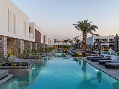 Piscina moderna dell'hotel con lettini e palme in un elegante resort al tramonto.