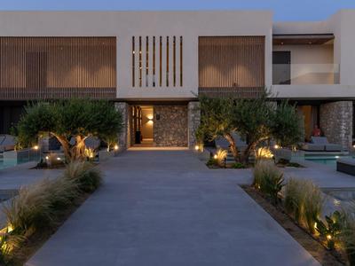 Esterno moderno dell'hotel con sentieri illuminati e ulivi al crepuscolo