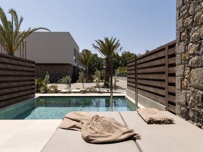 Modern pool area with lounge chair, towels, wooden privacy screens, and stone wall.