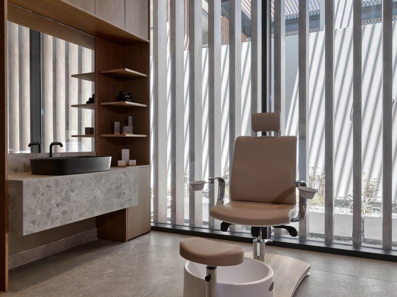 Modern bathroom with brown leather chair, sink, and large vertical windows.
